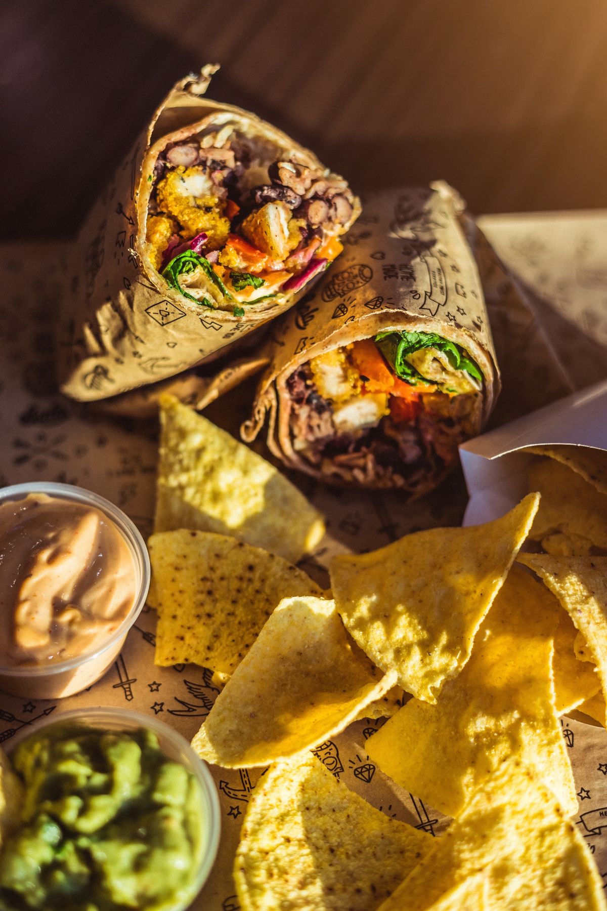 Burritos Bala cortados ao meio com nachos, guacamole e molhos