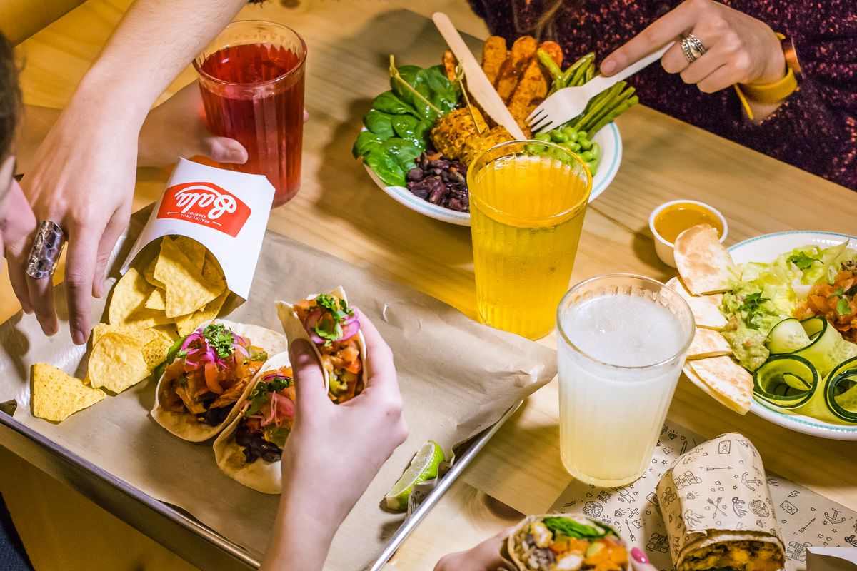 Grupo à mesa a partilhar tacos, nachos, bowls e burritos Bala
