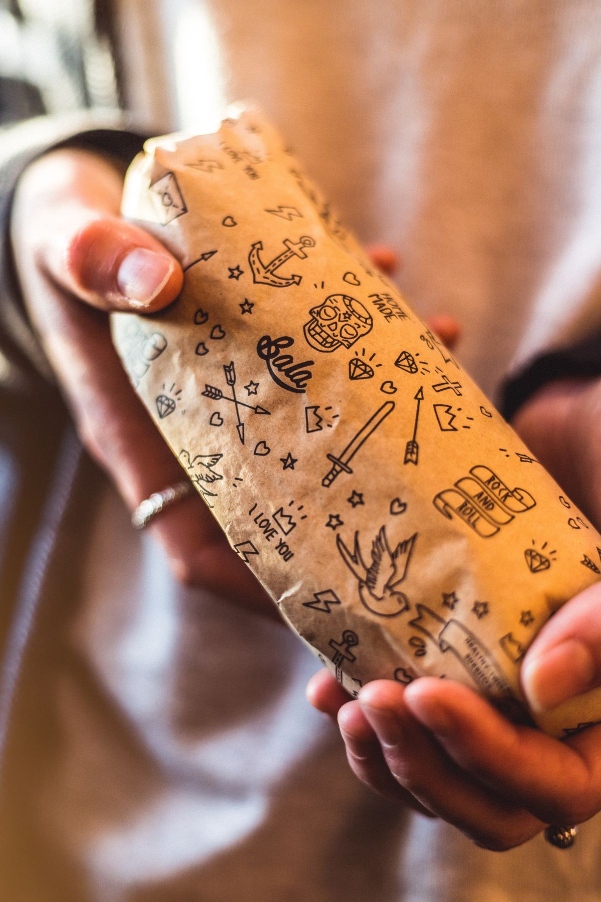 Mãos a segurar um burrito Bala embrulhado em papel kraft
