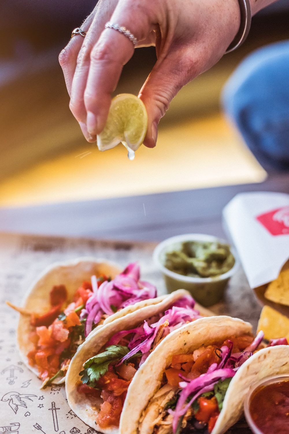 Mão a espremer lima sobre tacos acabados de montar